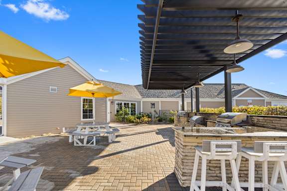 a patio with a barbecue grill and tables with umbrellas at The Winds at Poplar Creek Apartments , Schaumburg, 60194