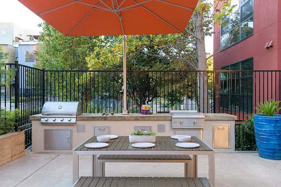 A patio with a table and an orange umbrella.