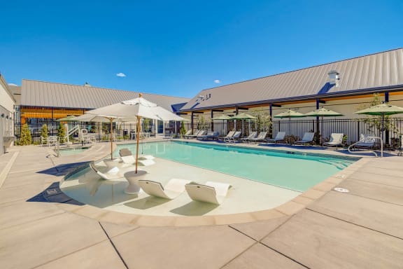 a pool with lounge chairs and umbrellas in front of a building at Westlook, Reno