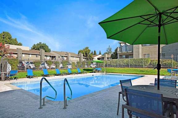 A green umbrella is next to a pool.