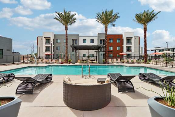 A pool surrounded by lounge chairs and palm trees at Ironwood Ranch Apartments,Maricopa,AZ,85138