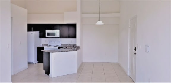 Mirabella Apartments kitchen area with white appliances and bar top for seating