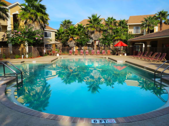 San Marco resort style swimming pool with lounge chairs and umbrellas at San Marco Apartments, Ormond Beach, Florida