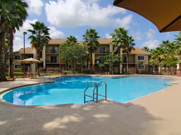 San Marco resort style swimming pool with lounge chairs and umbrellas at San Marco Apartments, Ormond Beach, FL, 32174