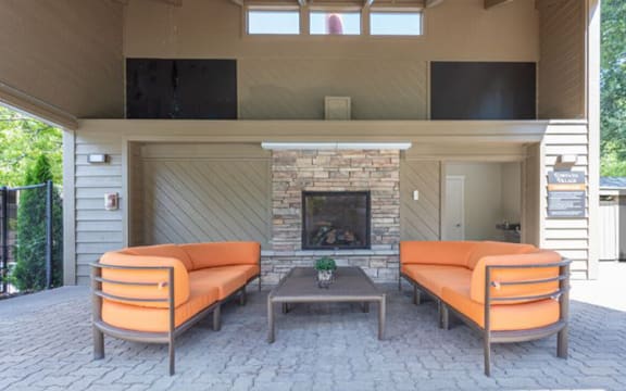 a patio with two orange couches and a fireplace