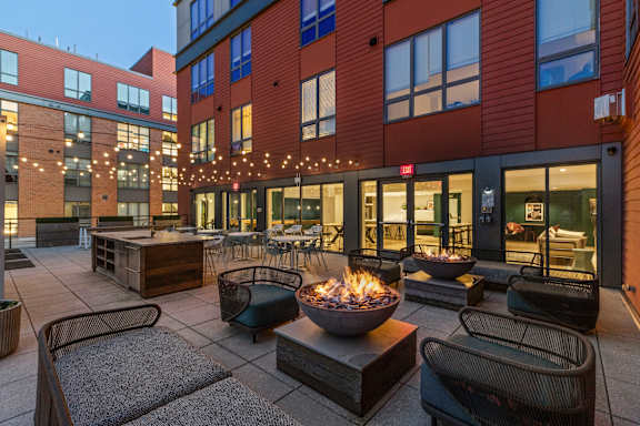 A patio with a fire pit and seating area at Trio Newton Apartments, Newton