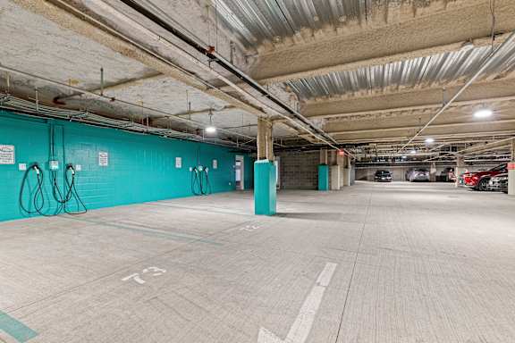 A parking garage with a blue wall and a green pillar. at Trio Newton Apartments, Apartments, Newton, MA