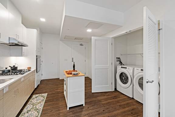 A kitchen with a washing machine and dryer in the laundry room. at Trio Newton Apartments, Newton, Massachusetts