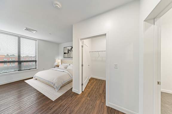 A bedroom with a bed, a window, and a wooden floor at Trio Newton Apartments, Apartments, Newton, MA