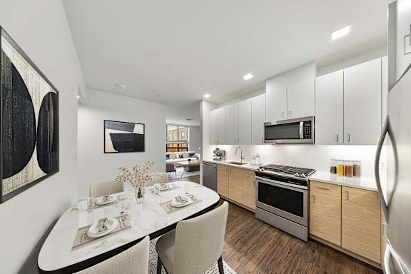 A modern kitchen with a dining table set for two. at Trio Newton Apartments, Massachusetts
