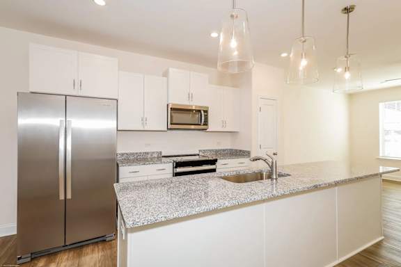 A modern kitchen with a stainless steel refrigerator and white cabinets.