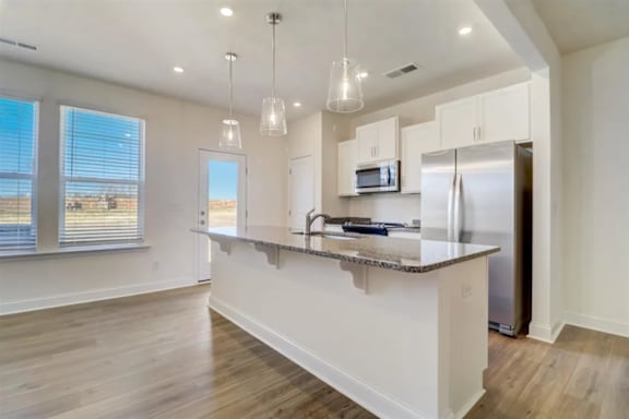 A kitchen with a granite countertop and stainless steel appliances.
