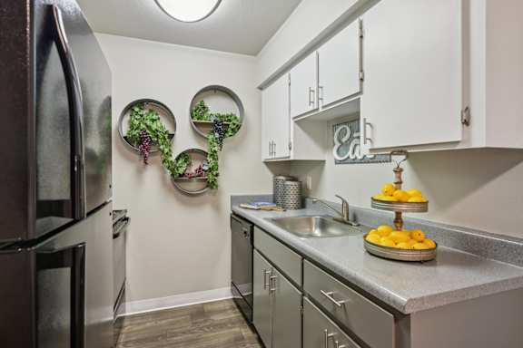 A kitchen with a black refrigerator and a white wall.