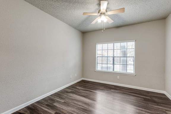 A room with a ceiling fan and a window with blinds.