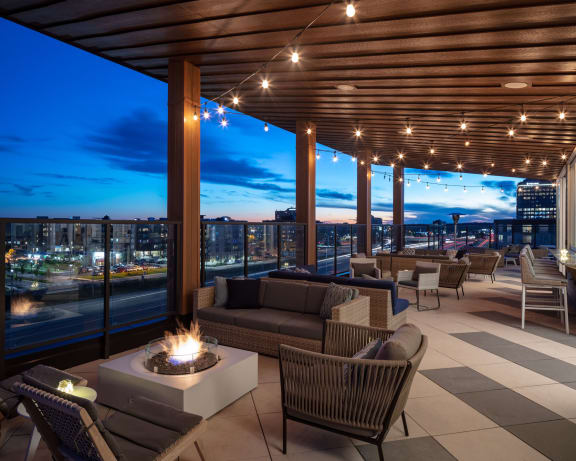 a roof top lounge with a fire pit and a view of the city