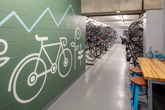 a row of bikes are lined up against a green wall with a blue and white arrow