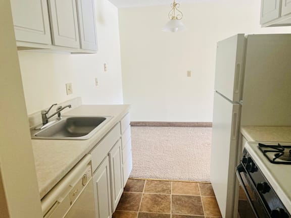 A kitchen with a sink, stove, and refrigerator.