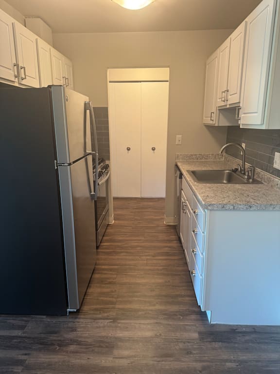 A kitchen with black fridge and white cabinets.
