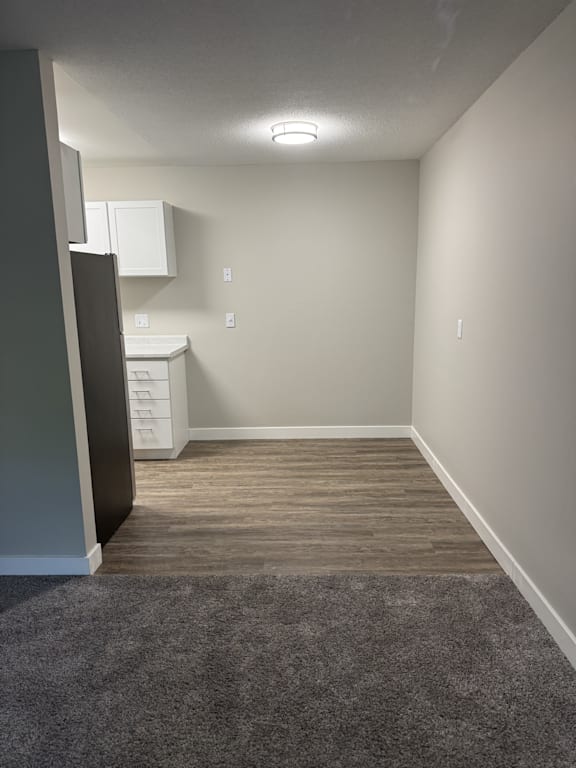 A kitchen area with a refrigerator, dishwasher, and a cabinet.