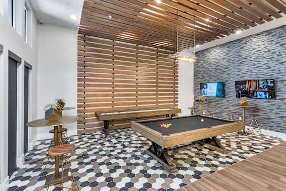 A room with a pool table and a bar stool.