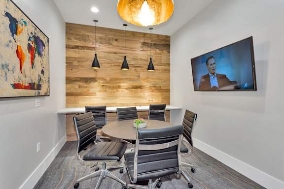 A conference room with a wooden wall and a television screen.