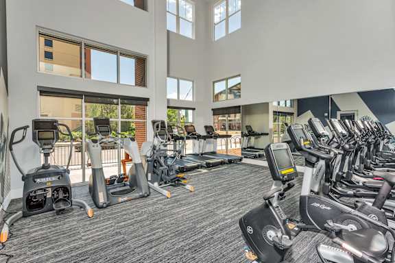 A gym with a variety of exercise equipment including treadmills, stationary bikes, and elliptical machines.