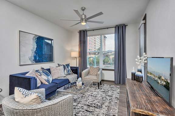 A living room with a blue couch and a ceiling fan.