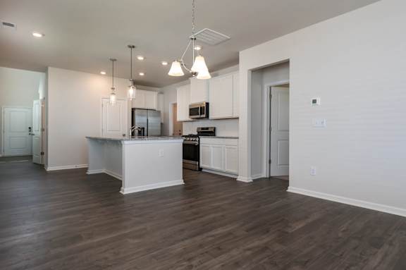 A kitchen with white cabinets and a wooden floor.