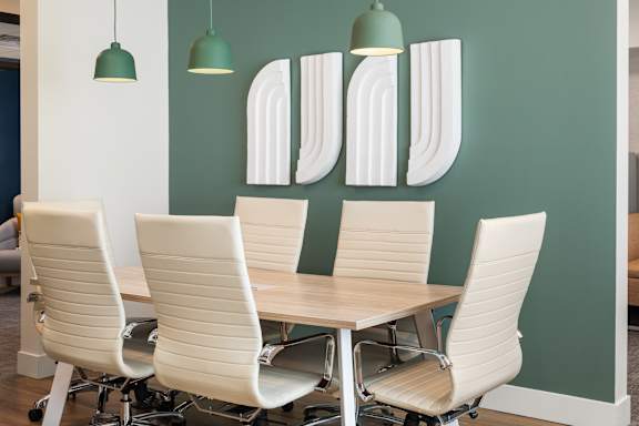 Four white chairs are arranged around a table in a room.