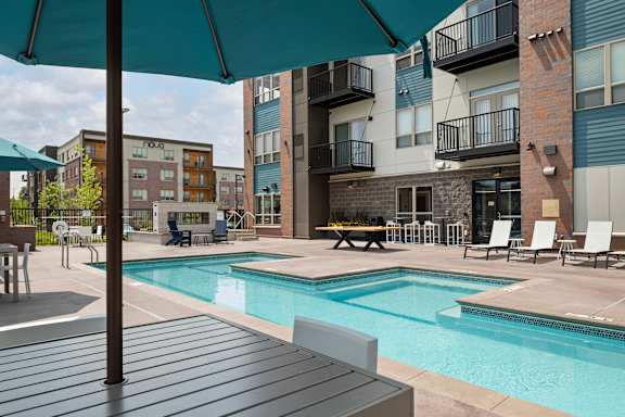 A pool area with a table and chairs and a bench.