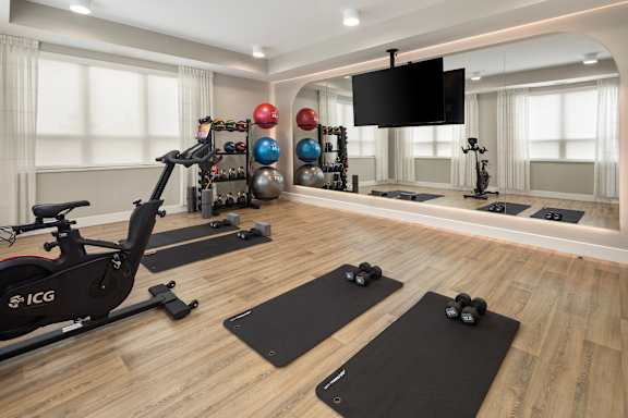 A home gym with a stationary bike, dumbbells, and a television.