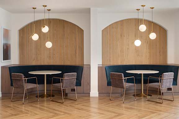 Two round tables with chairs and hanging lights in a room.