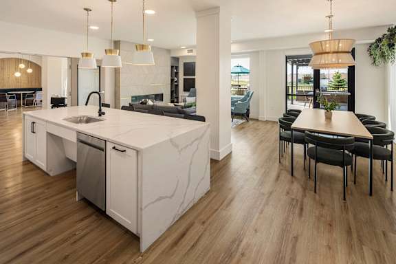 A modern kitchen with a marble island and wooden floors.