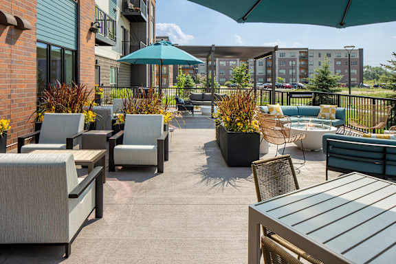 A patio with a table and chairs and a green umbrella.