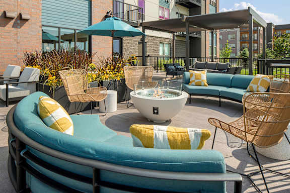 A patio with a fire pit and chairs.
