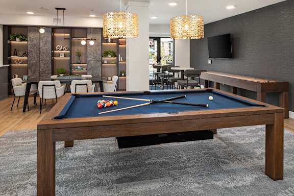 A pool table in a room with a TV and a bar.