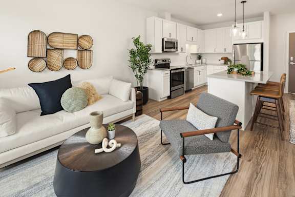 A modern living room with a white sofa, grey armchair, and a wooden coffee table.