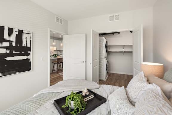 A bedroom with a bed, a tray with a plant on it, and a painting on the wall.