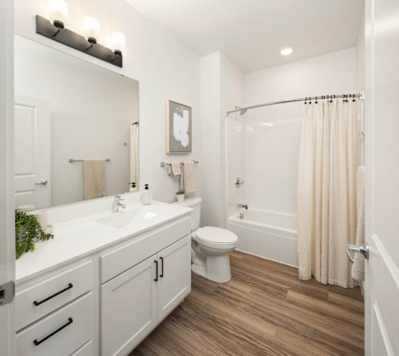 A white bathroom with a toilet, sink, and shower.