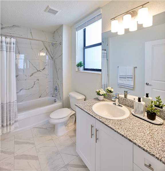 A bathroom with a marble shower and a white toilet.