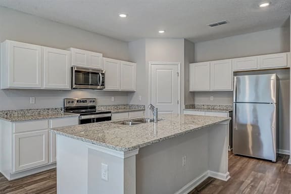 A kitchen with white cabinets and granite countertops.