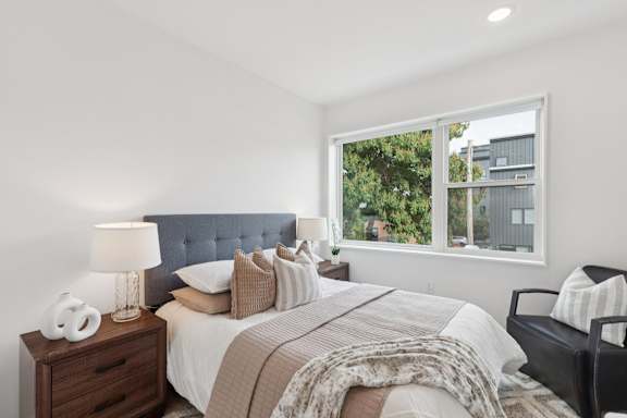 A bedroom with a bed, nightstand, and chair.