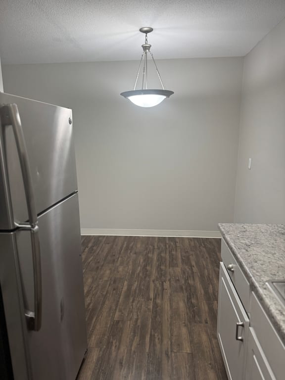 A kitchen with a stainless steel refrigerator and wooden flooring.