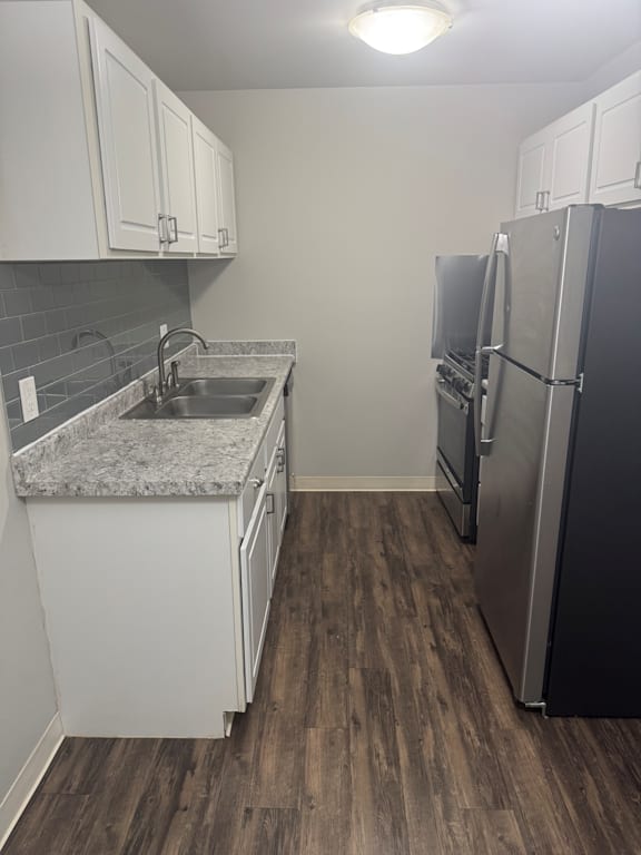 A kitchen with a sink, refrigerator, and cabinets.