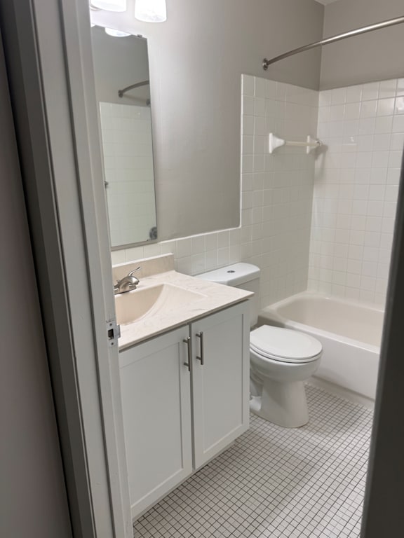 A white toilet sits in a bathroom next to a sink and a bathtub.