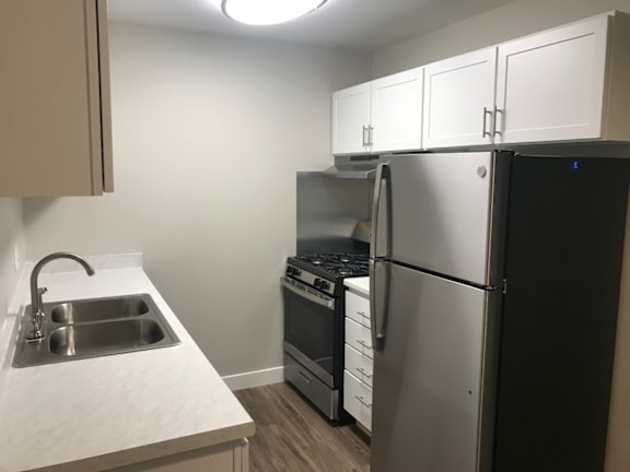 A kitchen with a sink, stove, and refrigerator.