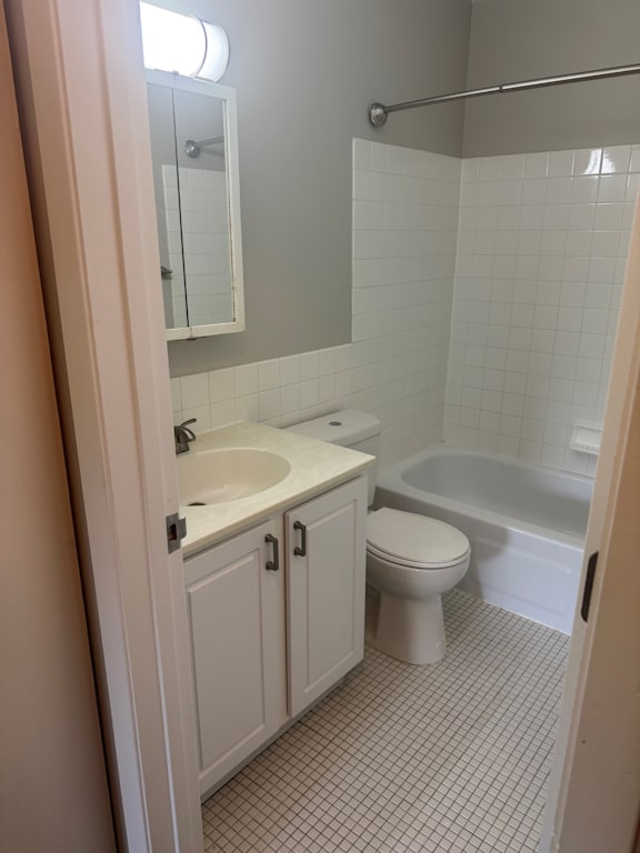 A white toilet is in a bathroom with a sink and tub.