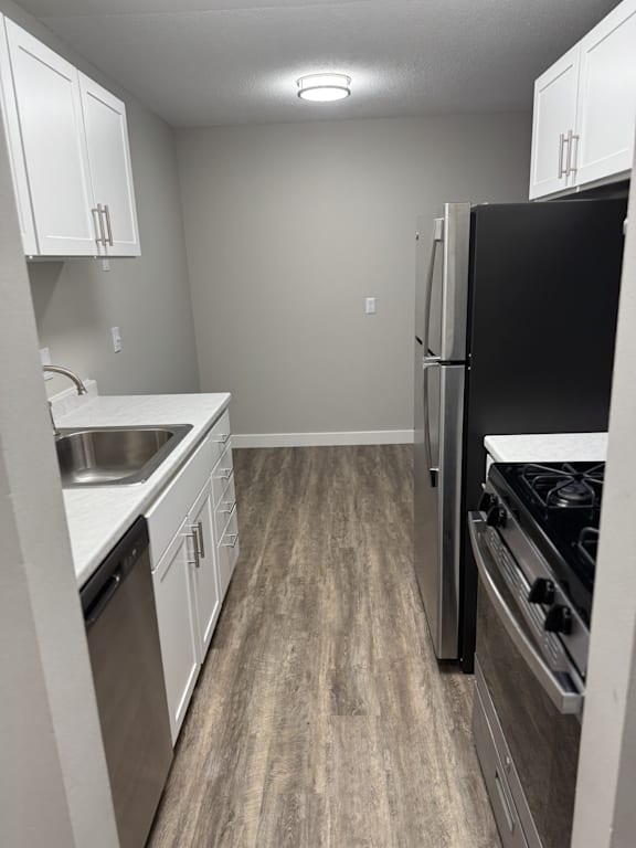 A kitchen with a black refrigerator, white cabinets, and a wooden floor.