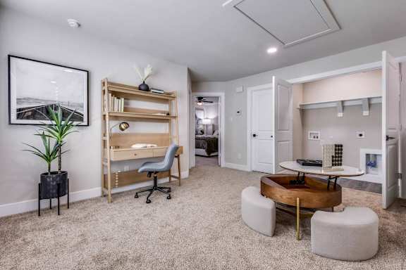 A room with a desk, chairs, and a plant.