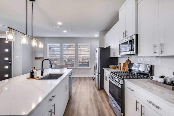 A modern kitchen with white cabinets and a black stove top oven.
